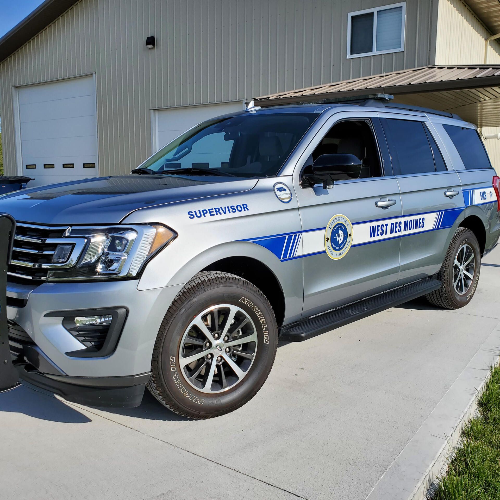 A silver suv with the word duty on the side is parked in front of a building