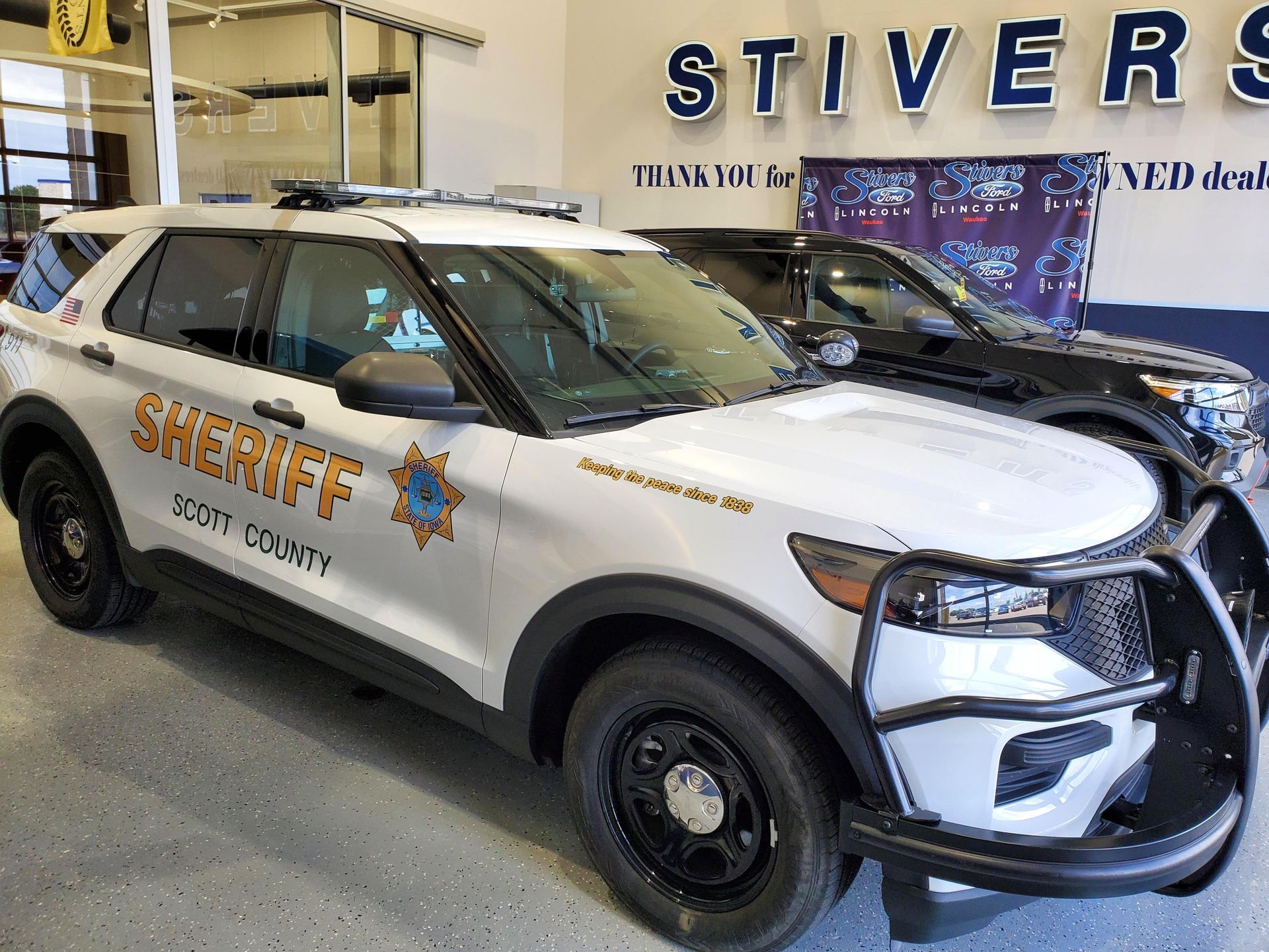 A white sheriff 's car is parked in a garage.