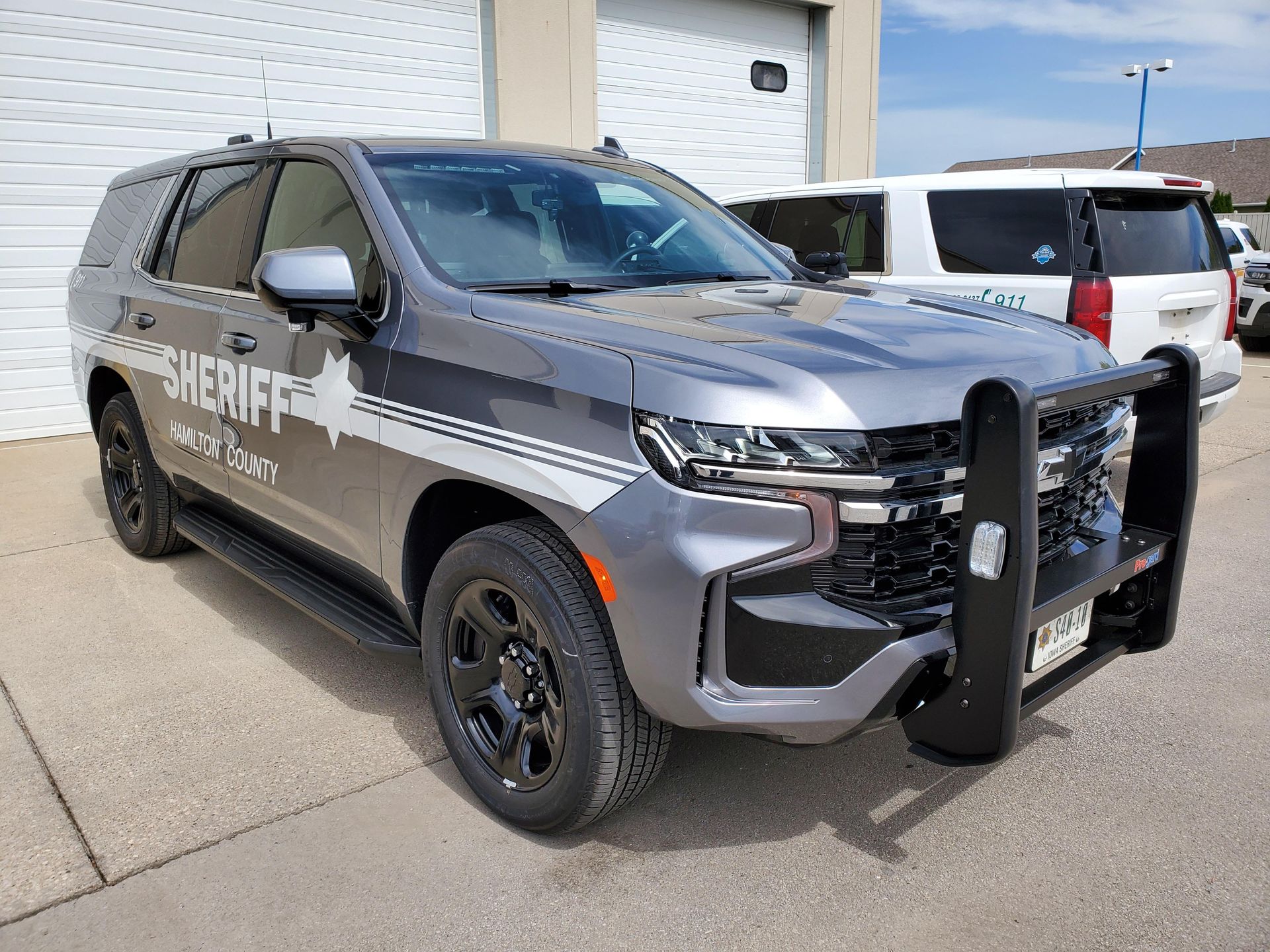 A sheriff 's car is parked in front of a garage.