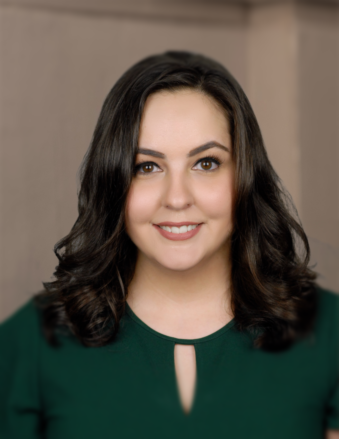A woman in a green shirt is smiling for the camera.
