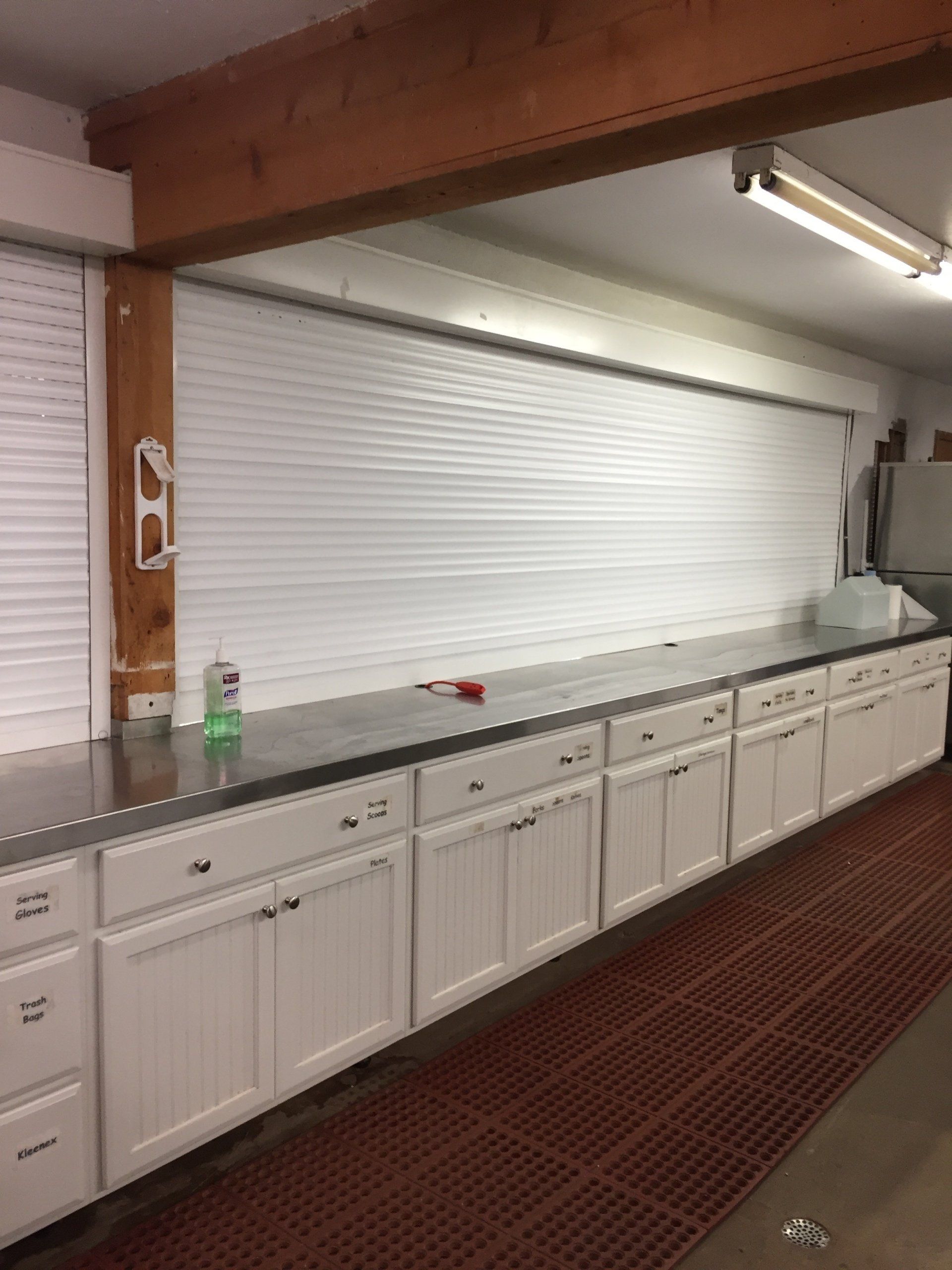 White cabinets with black countertop under a white window blind in a garage.