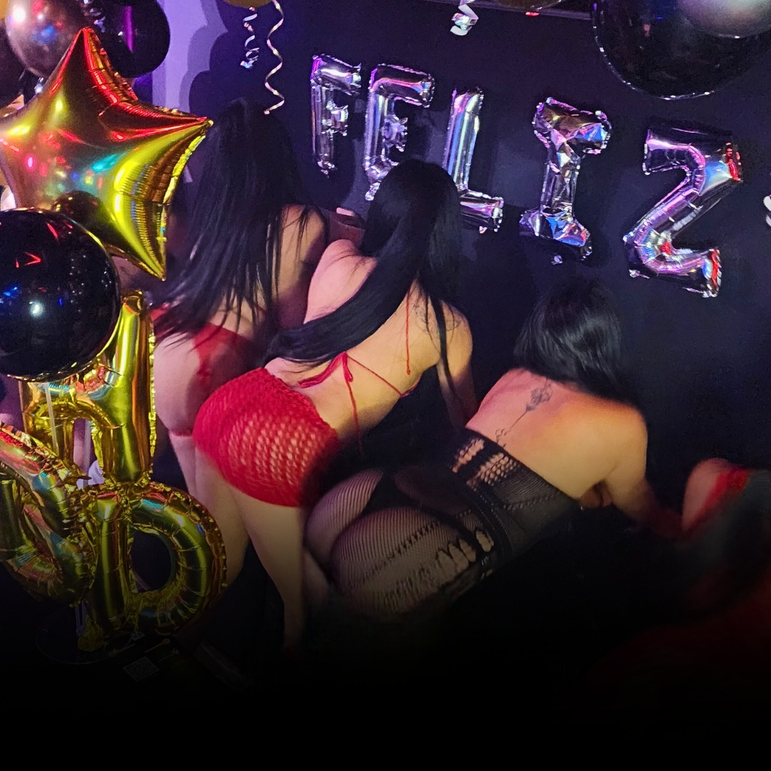 Tres mujeres en lencería posan cerca de globos "FELIZ".