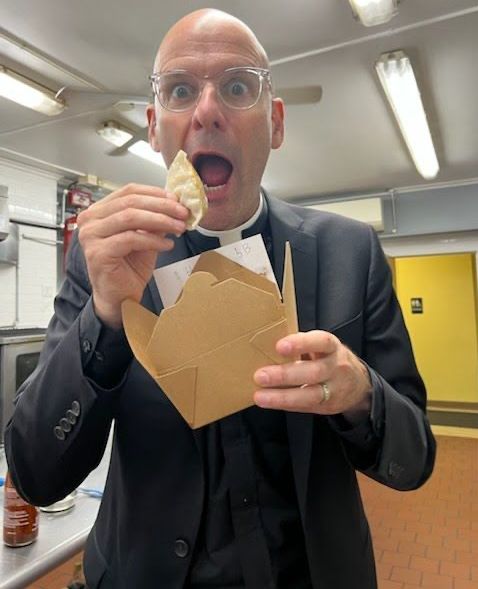 A man in a suit is eating something out of a cardboard box