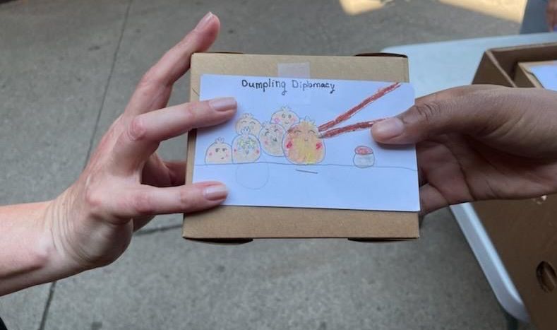 A person is holding a cardboard box with a drawing on it