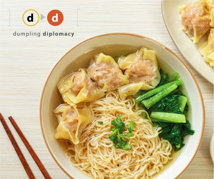A bowl of dumplings and noodles with chopsticks on a table