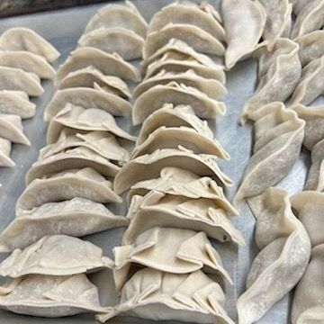 A tray of dumplings sitting on top of each other on a table.