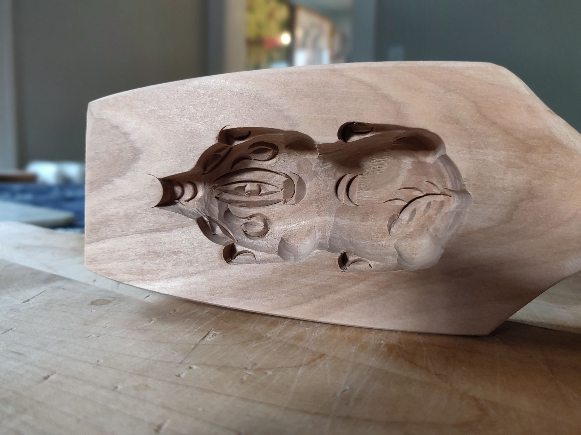 A wooden sculpture of a pig is sitting on a wooden table.