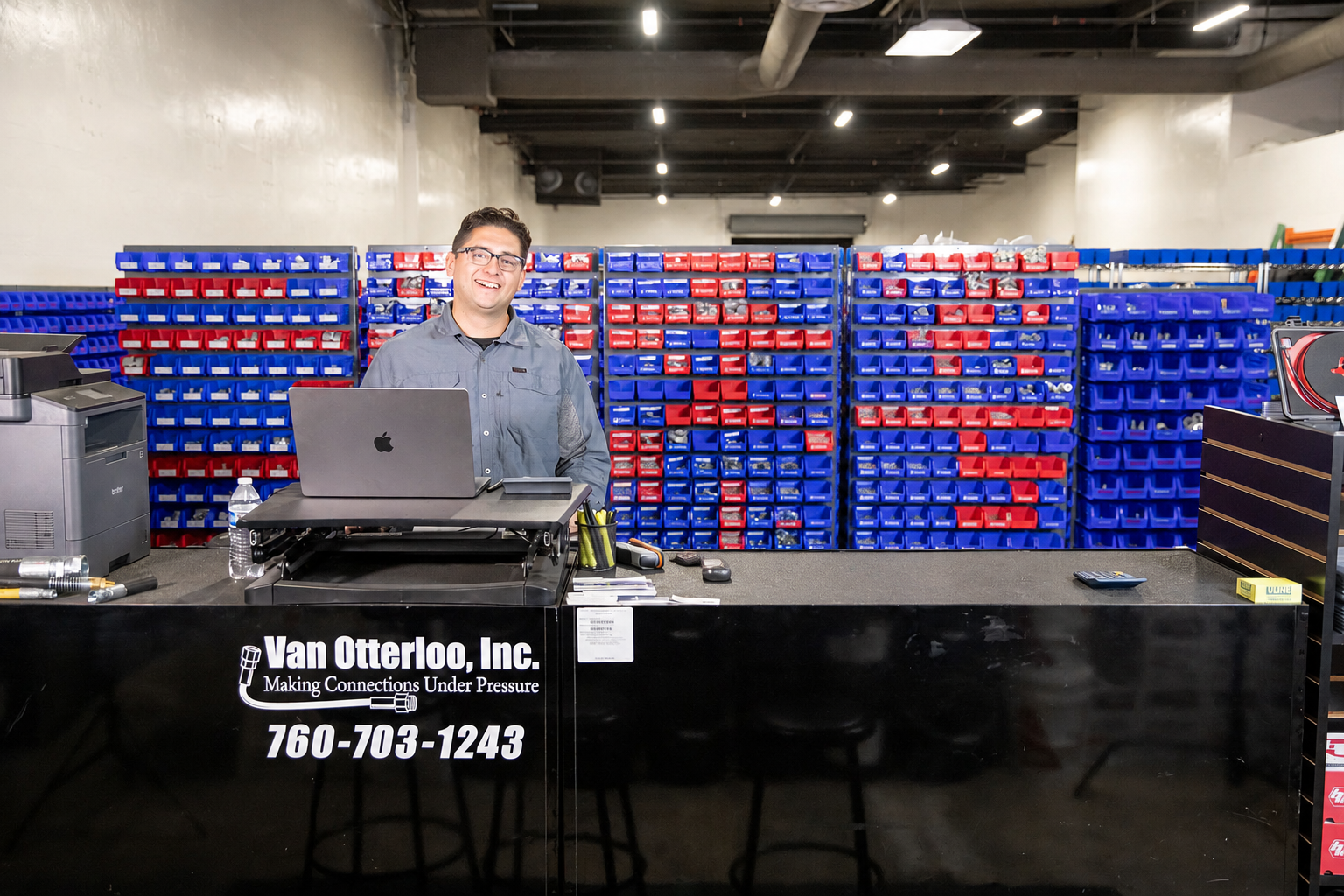 Two men are sitting at a desk with the Van Otterloo, Inc. logo laptops in a store.
