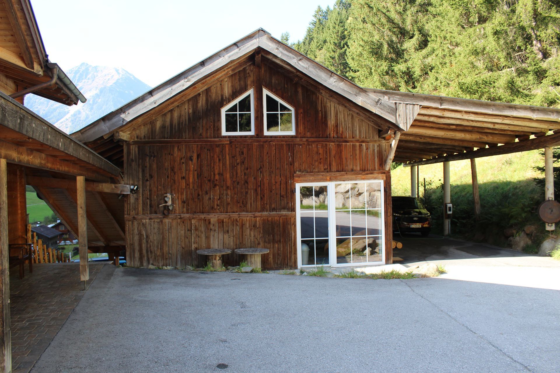 Ein hölzernes Gebäude im alpinen Stil mit einem Kiesparkplatz