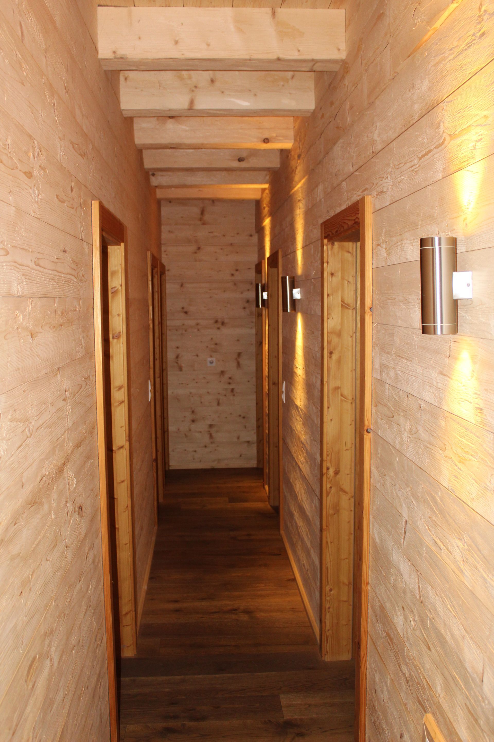 Ein schmaler Flur mit hellen Holzplankenwänden,
