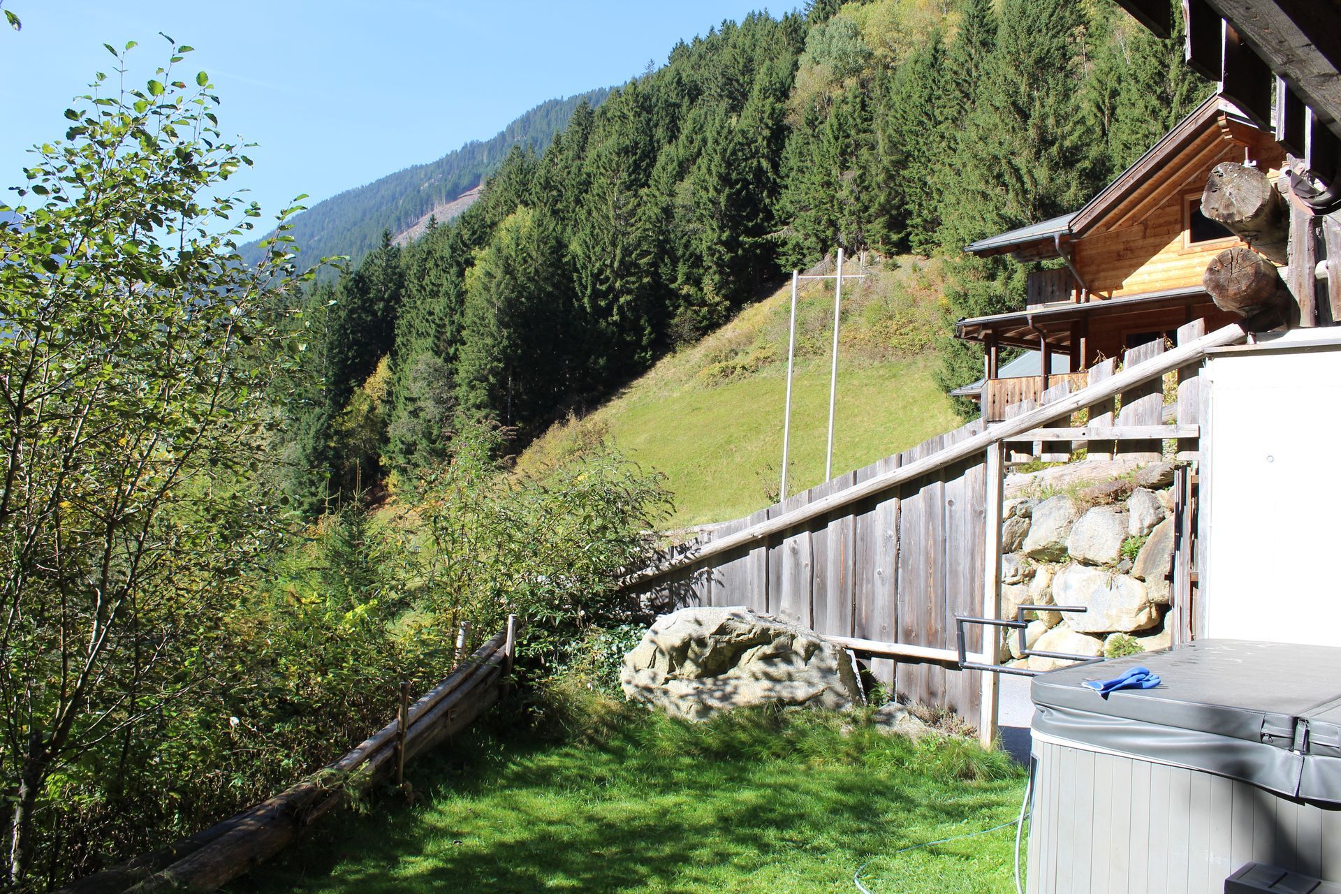 Ein Holzzaun verläuft entlang eines grasbewachsenen Hangs