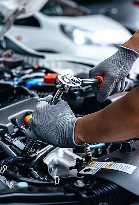 A person is working on a car engine with a wrench.