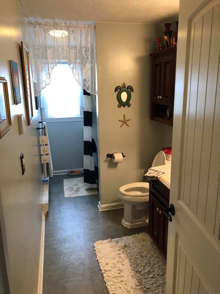 A bathroom with a toilet , sink , and shower curtain.