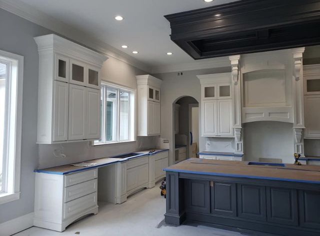A kitchen with white cabinets and a black island.