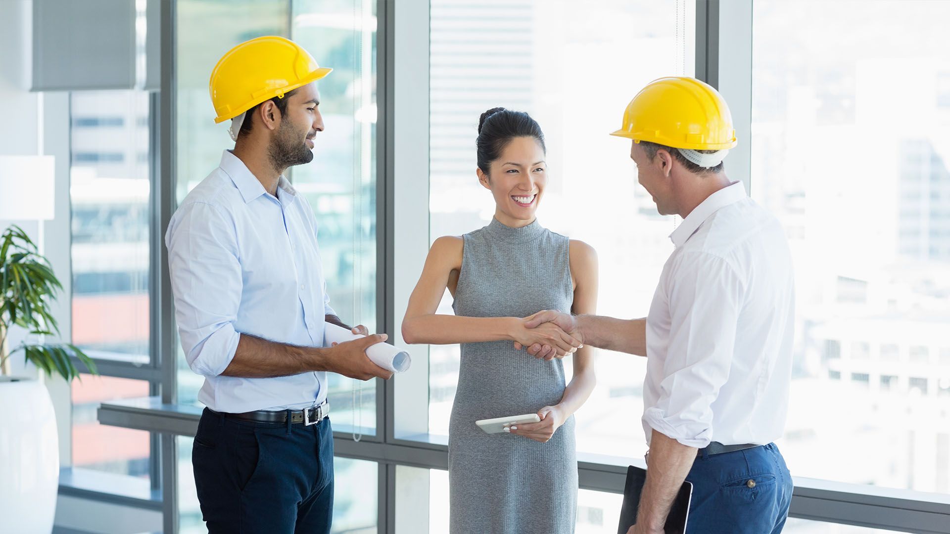 A group of construction workers are shaking hands with a woman.