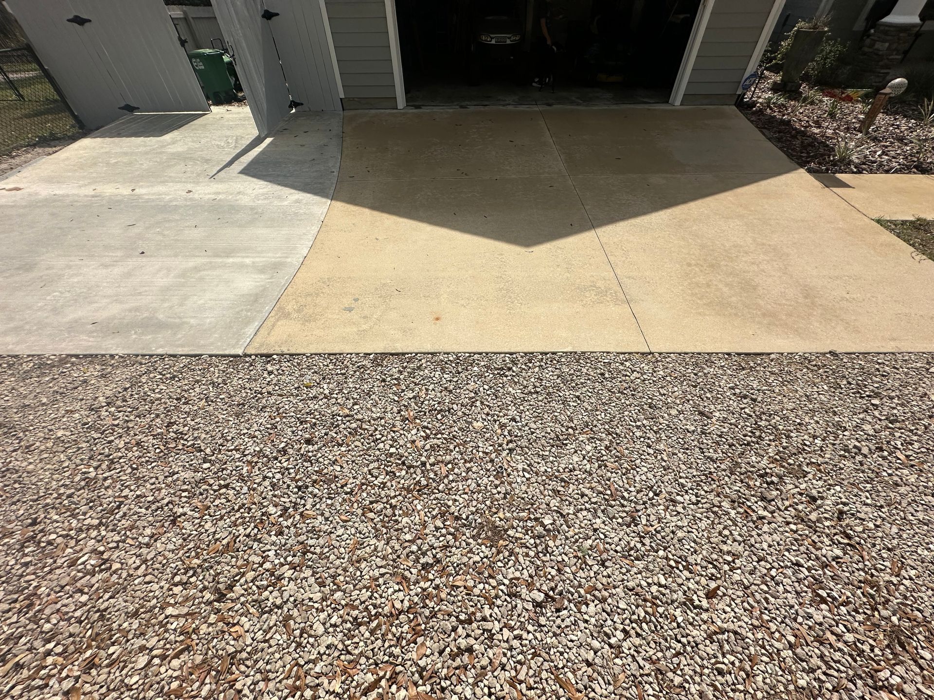 A driveway with gravel and concrete in front of a garage.