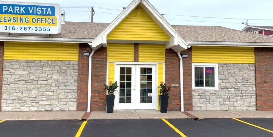 Park Vista leasing office building with yellow and stone exterior. Double doors and window visible.