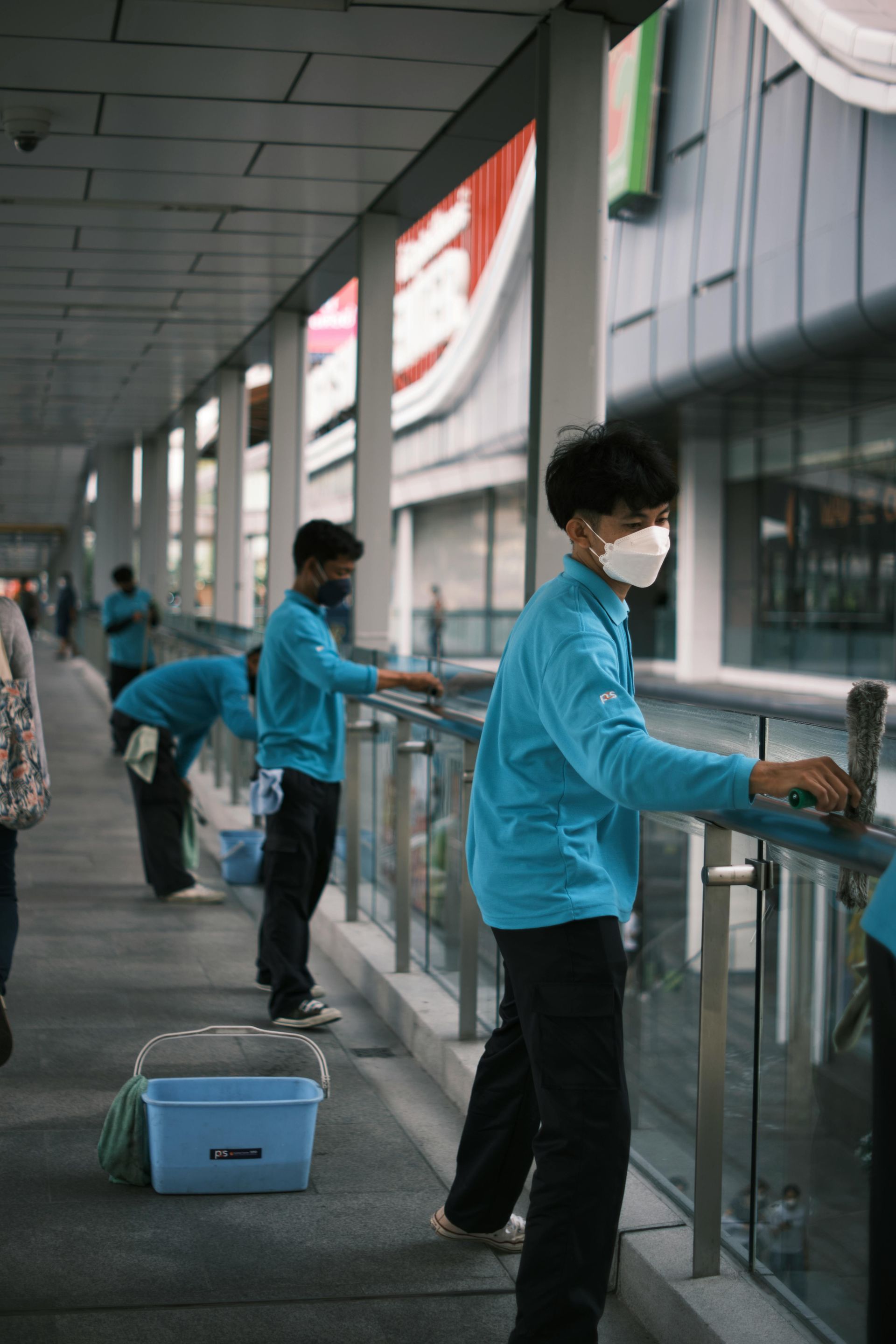 Professional cleaning staff sanitizing handrails in commercial building