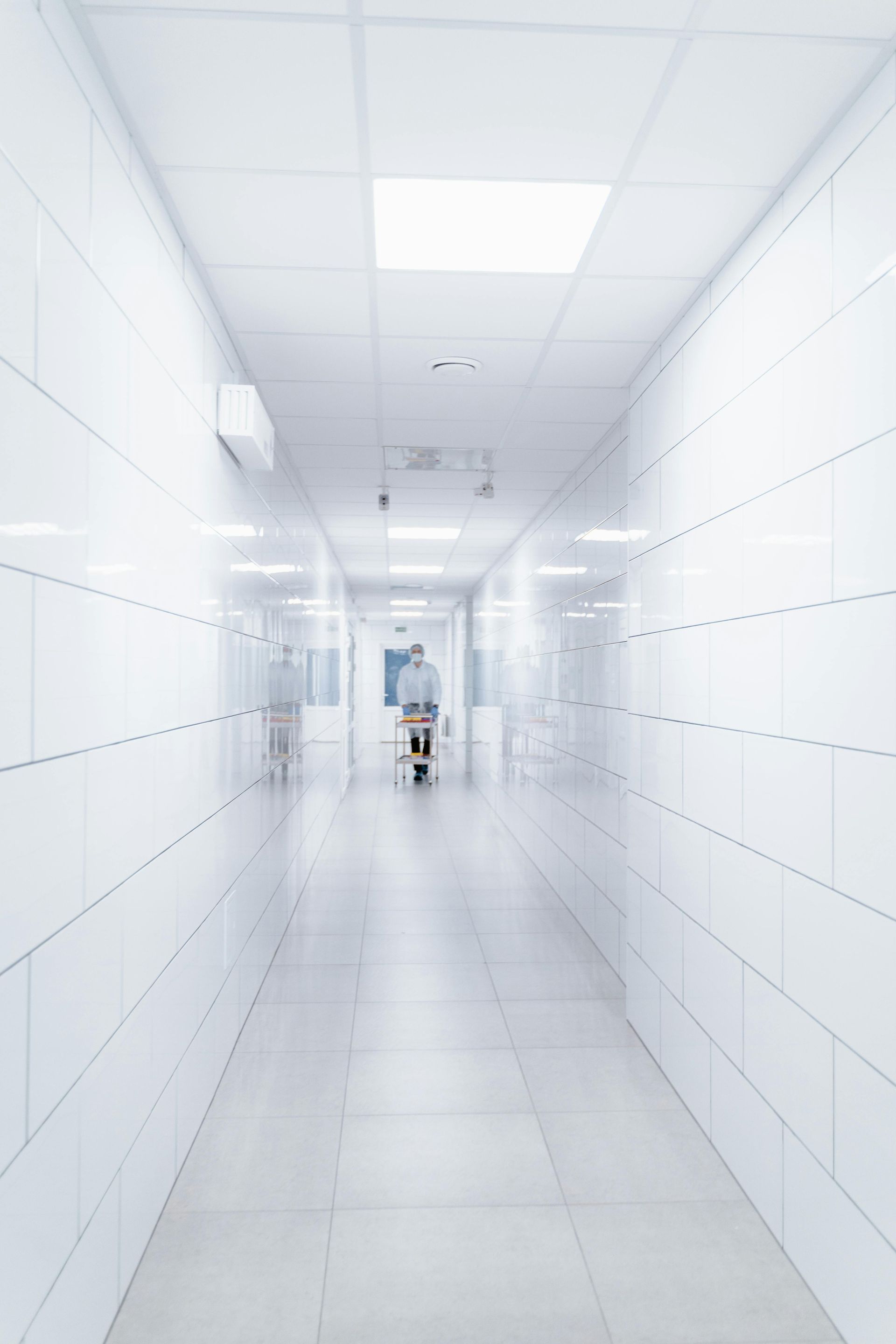 Sterile white hospital corridor with tiled floors and ceiling lights, featuring pro cleaning