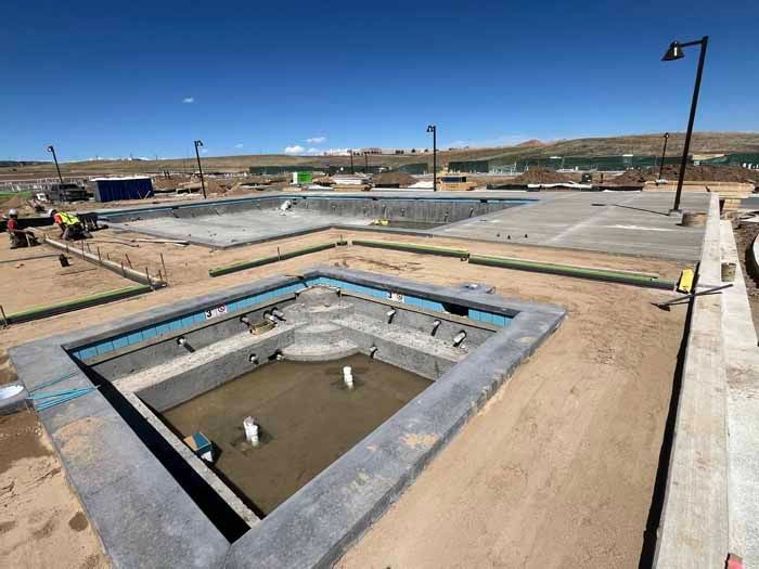 Pools under construction in a desert environment, with concrete forms and exposed plumbing.