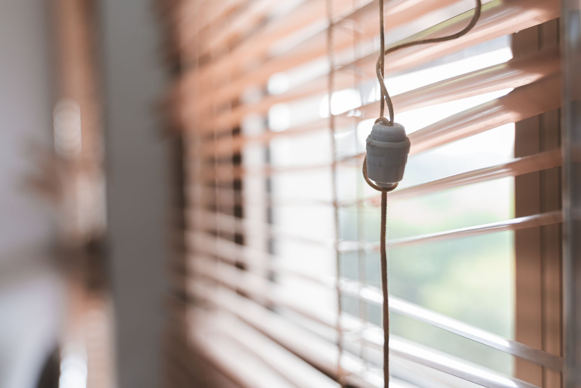 A tangled pull cord on a set of window blinds that needs professional repair 
