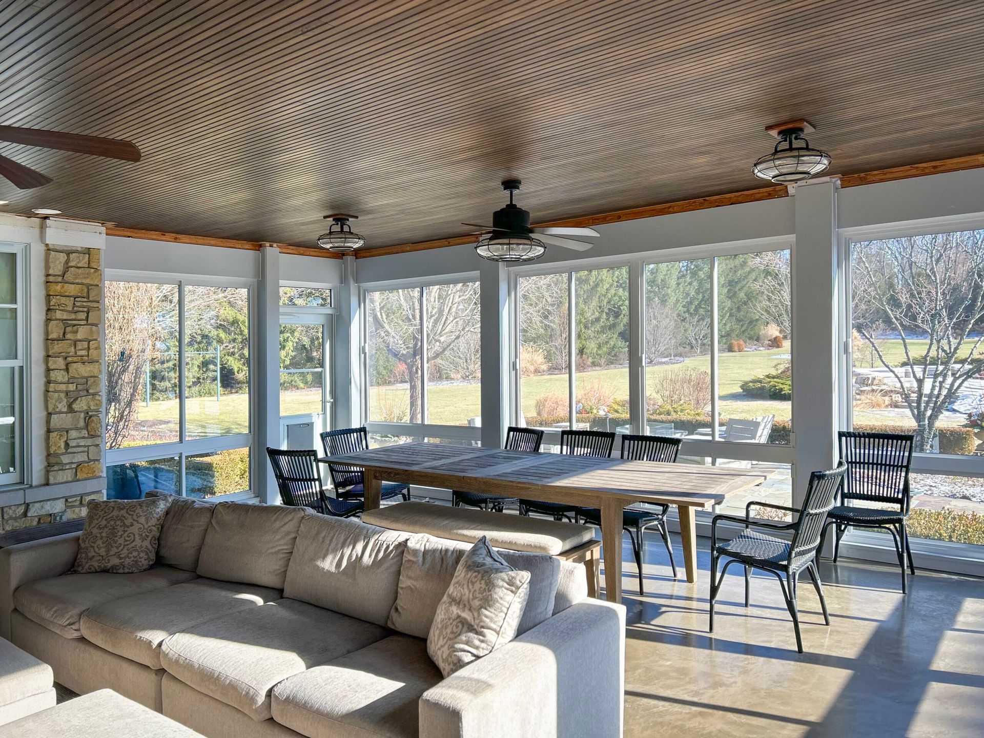 Sunroom with large windows, dining table, seating, and a decorative ceiling.