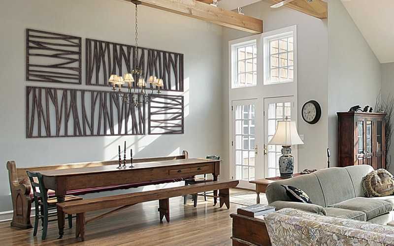 Dining room with a long wooden table, benches, and unique abstract rectangular wall art, near a couch and French doors.