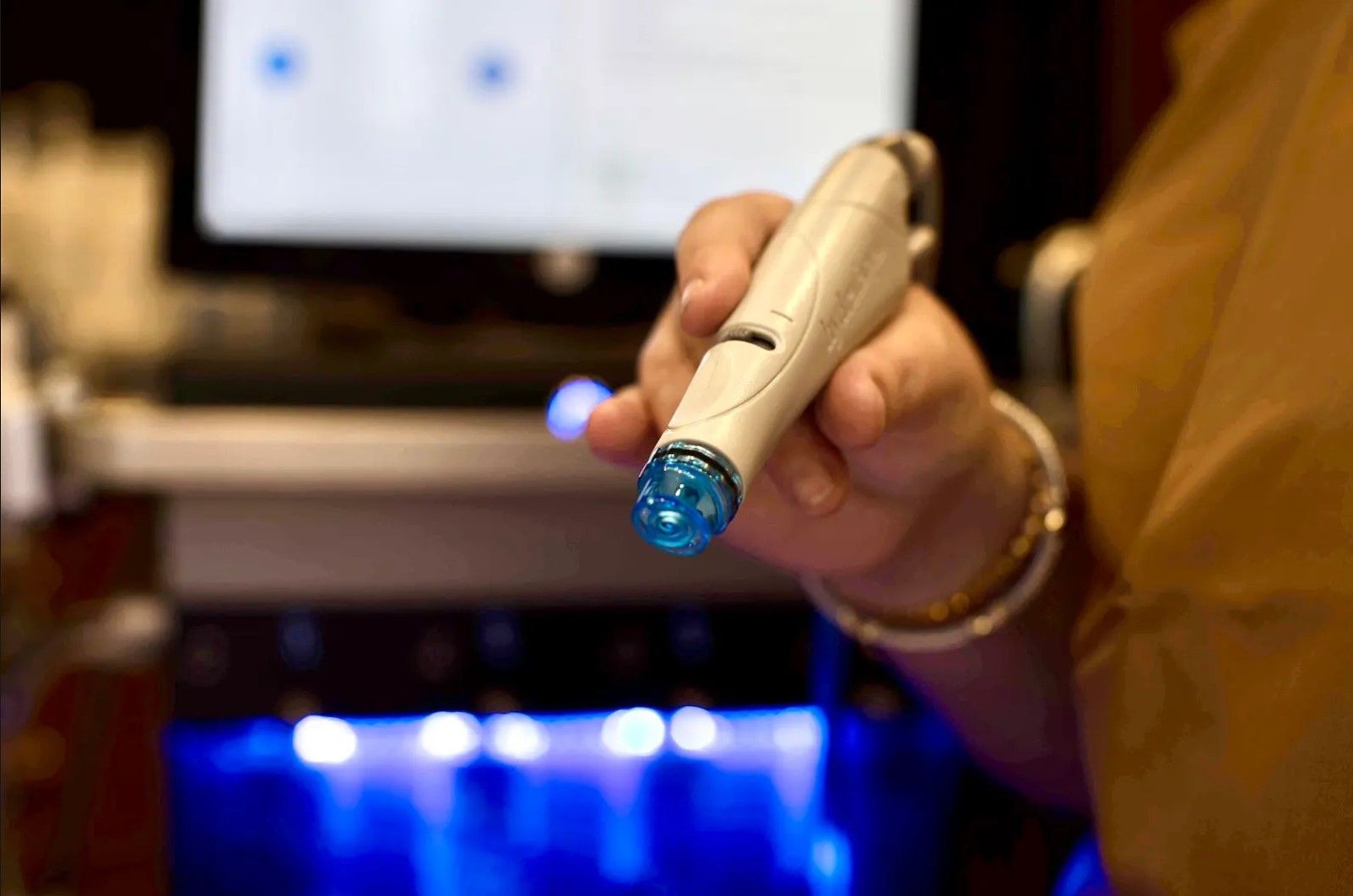A person is holding a pen in front of a computer screen.
