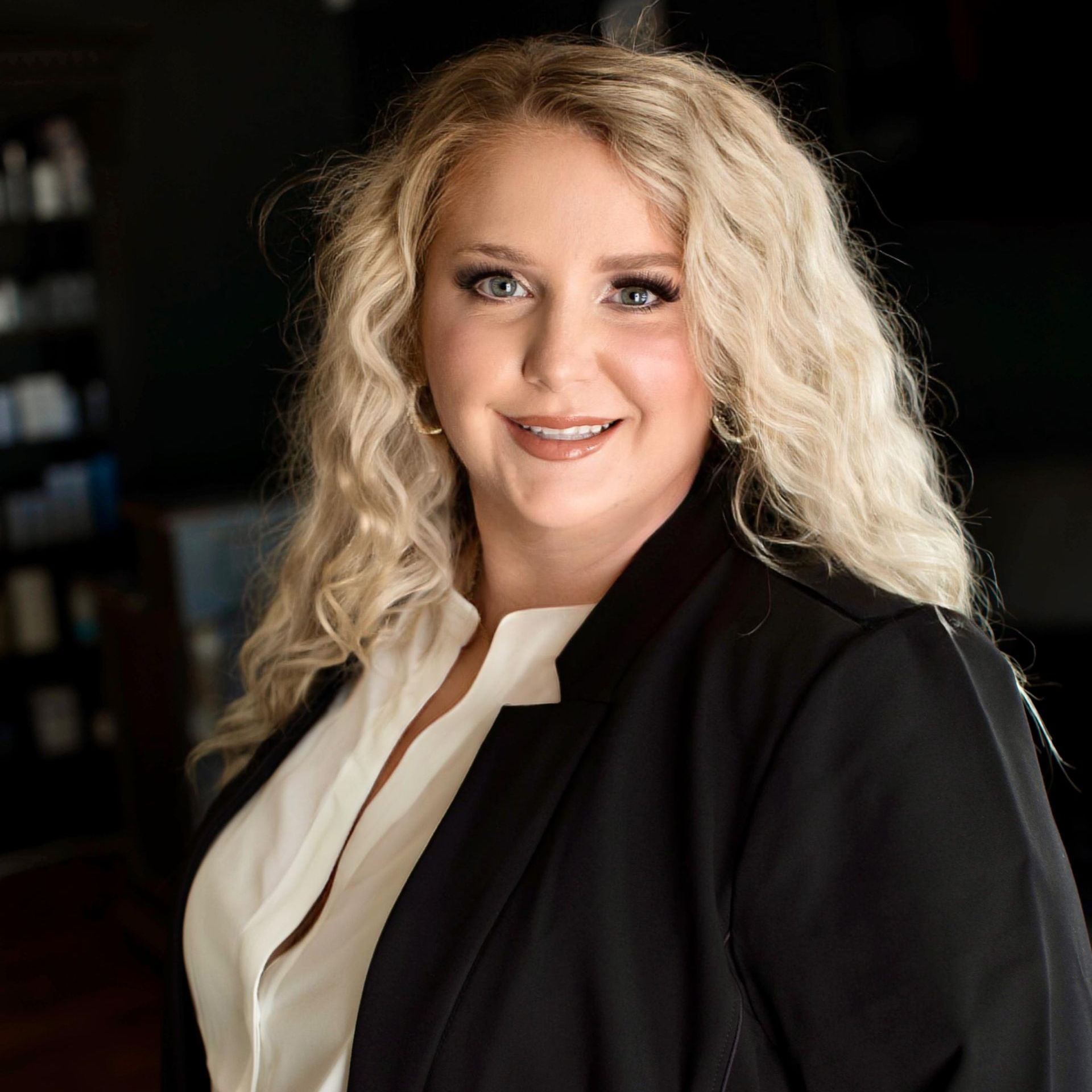 A woman in a black jacket and white shirt is smiling for the camera.