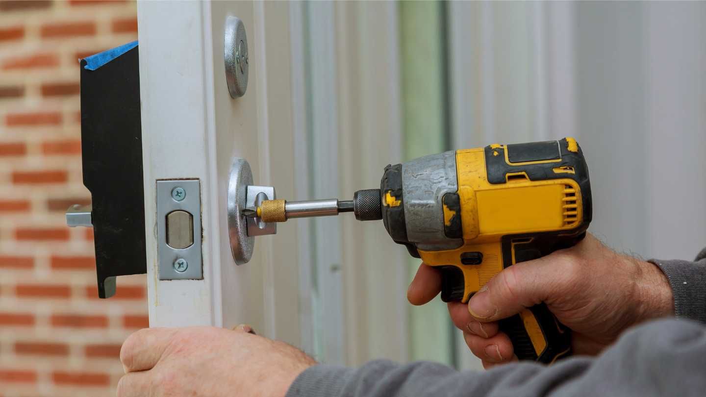 A person is using a power drill to install a door lock