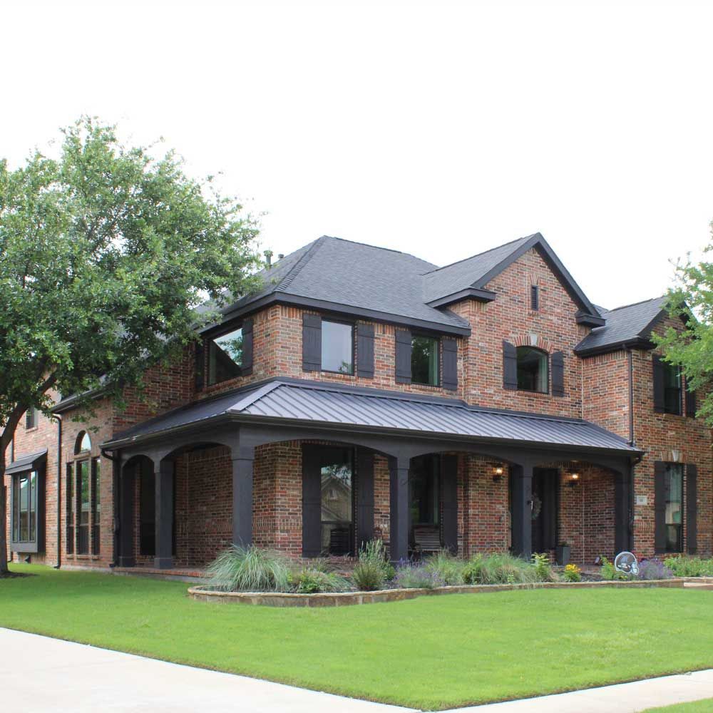 A large brick house with a black roof and black shutters