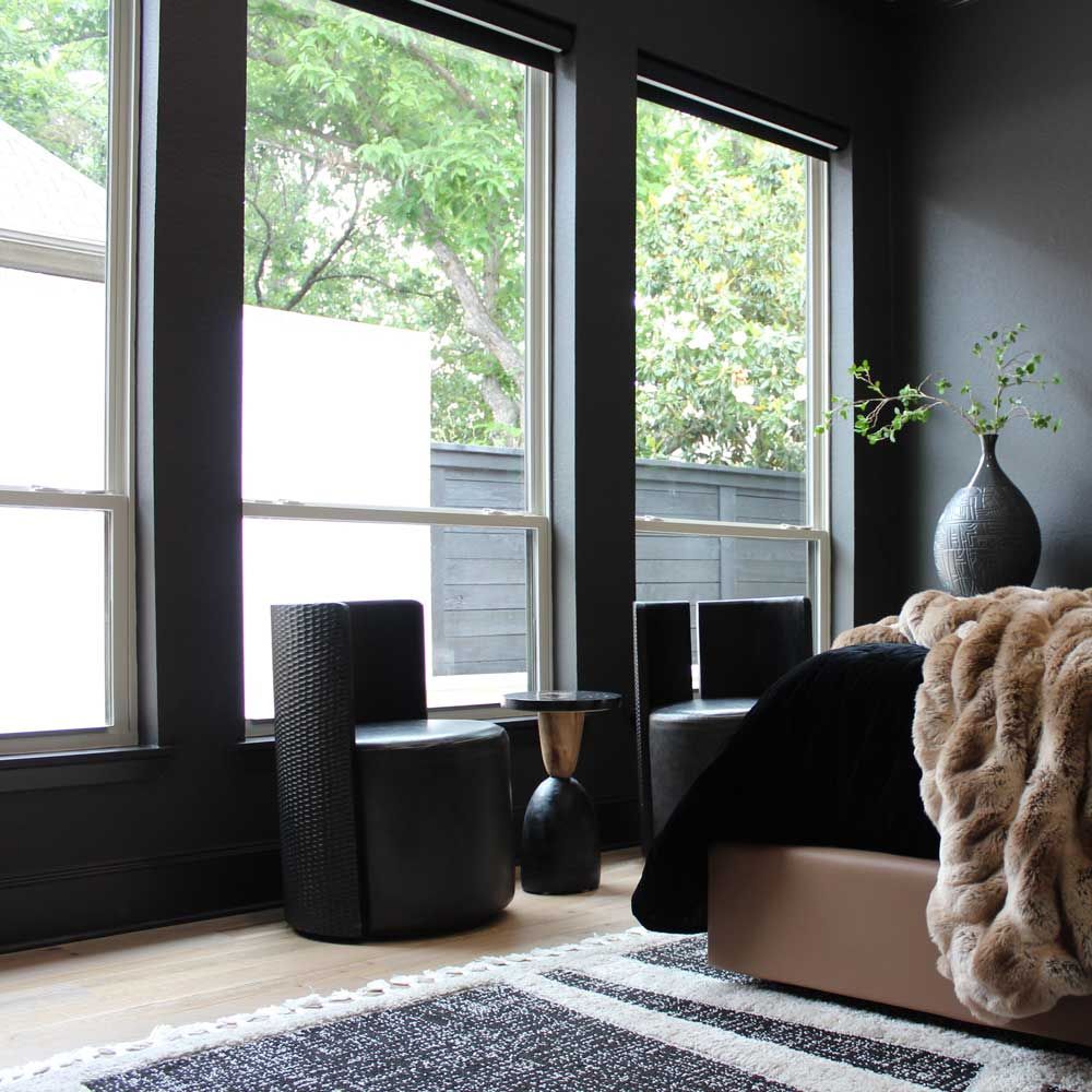 A bedroom with black walls and a large window