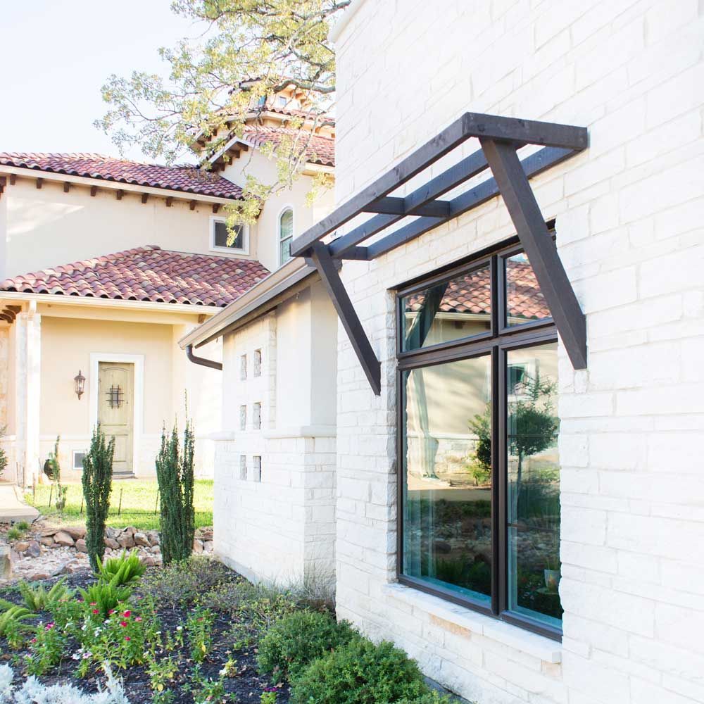 A white brick building with a window with a canopy over it