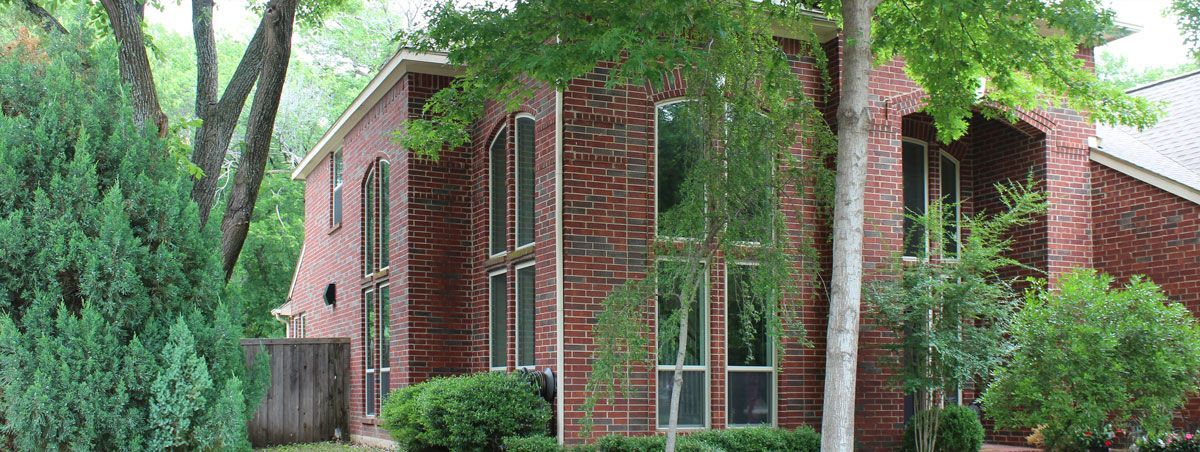 A large brick house with lots of windows and trees in front of it.