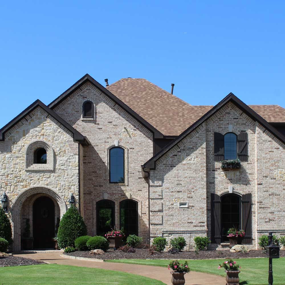 A large brick house with a blue sky in the background