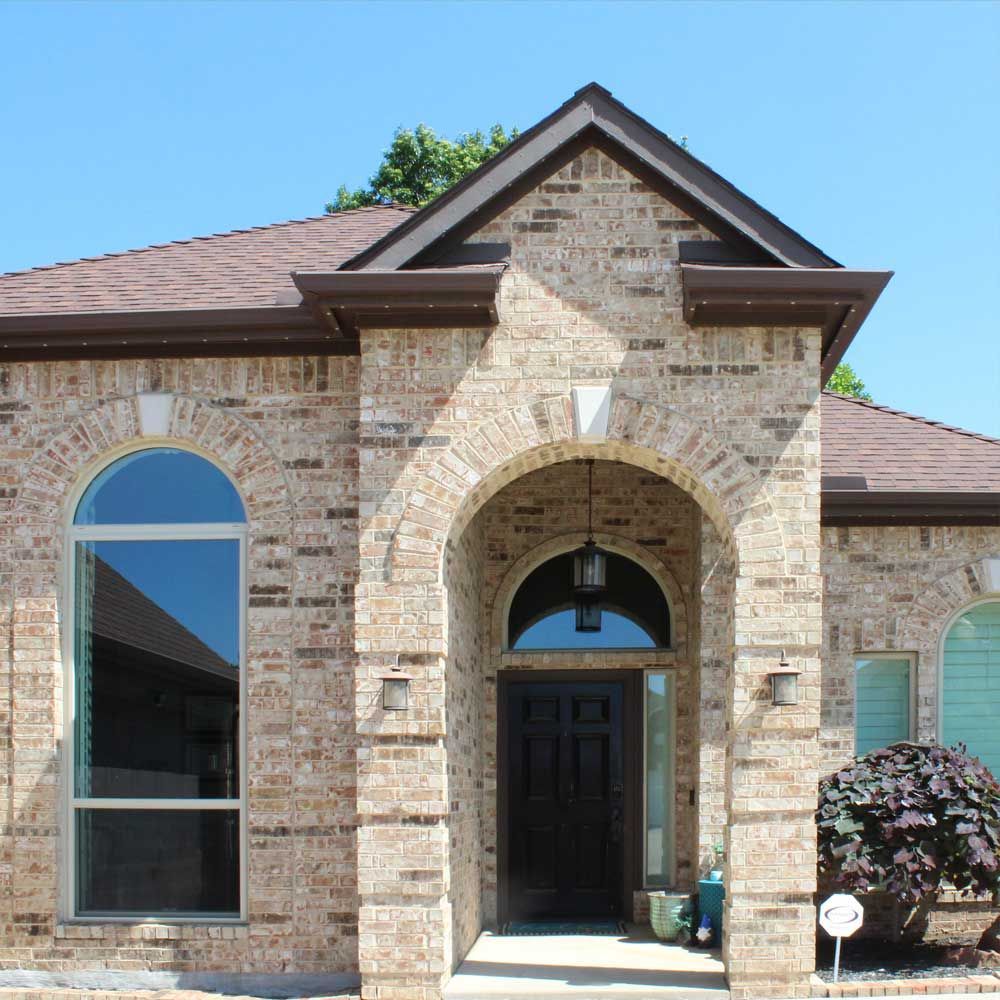 A brick house with arched windows and a brown roof