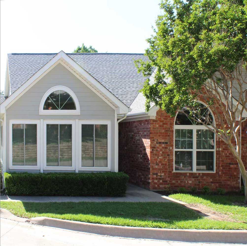 A brick house with a gray siding and white windows