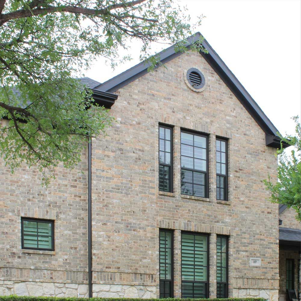 A brick building with three windows and a black roof