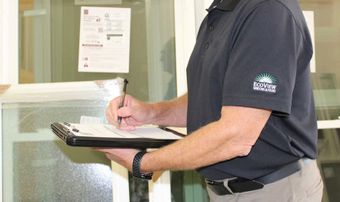 A man is holding a clipboard and writing on it.