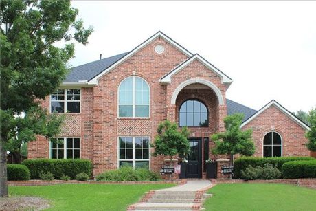 A large brick house with a brown roof, new window replacements and an entry door