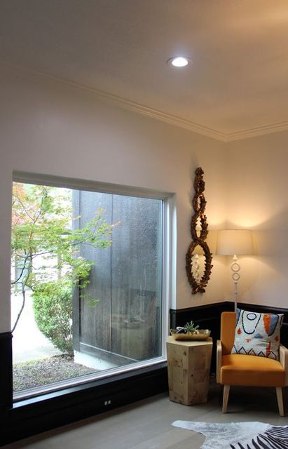 A living room with a large window and a chair.