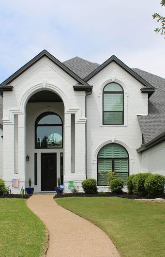 A large white house with a walkway leading to the entry door replacement