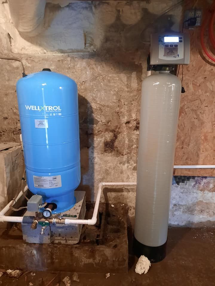 a water tank is sitting next to a water filter in a basement .