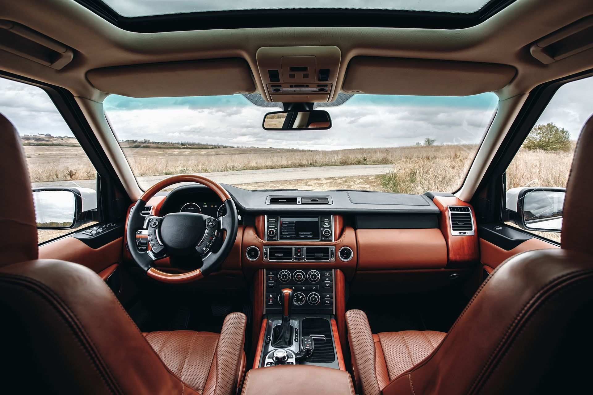 Interior view of a brown leather Range Rover, showing the dashboard, steering wheel, and front seats.