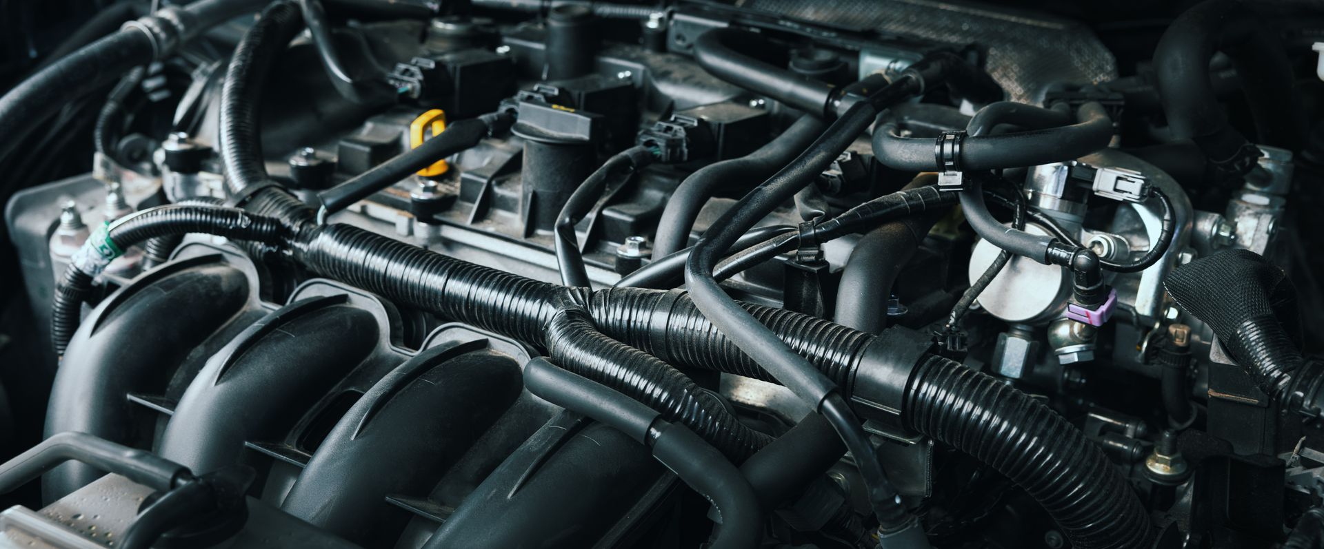 Engine bay of a car, showing various tubes, pipes, and components in a dark setting.