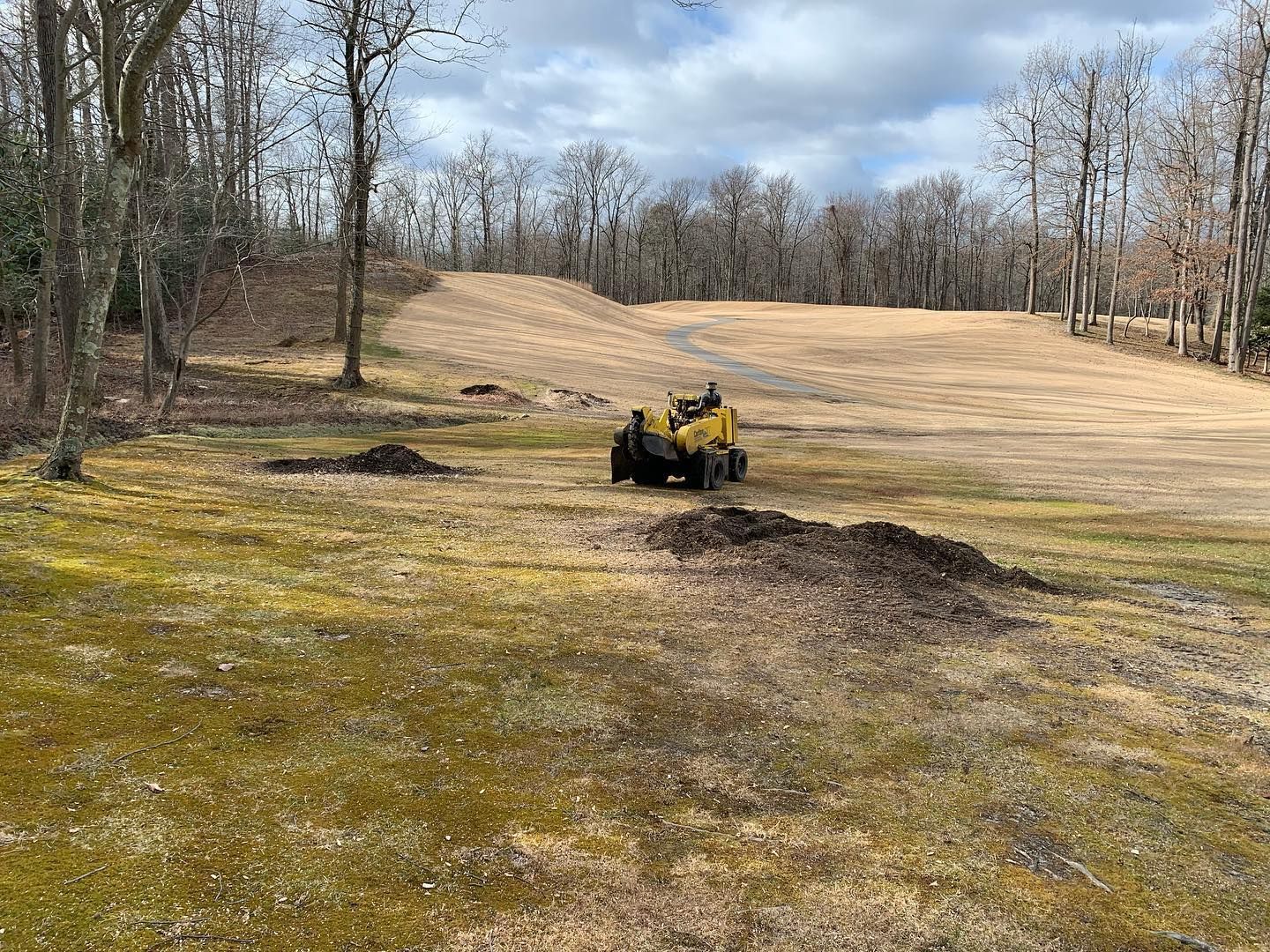A yellow atv is driving down a dirt road in a field.