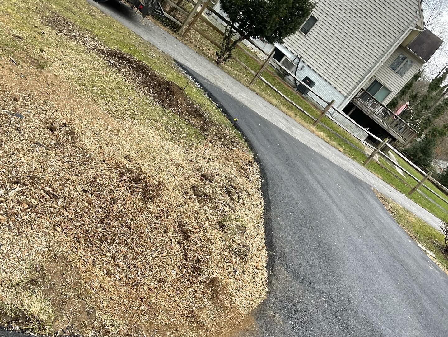 A pile of mulch is sitting on the side of a road next to a house.