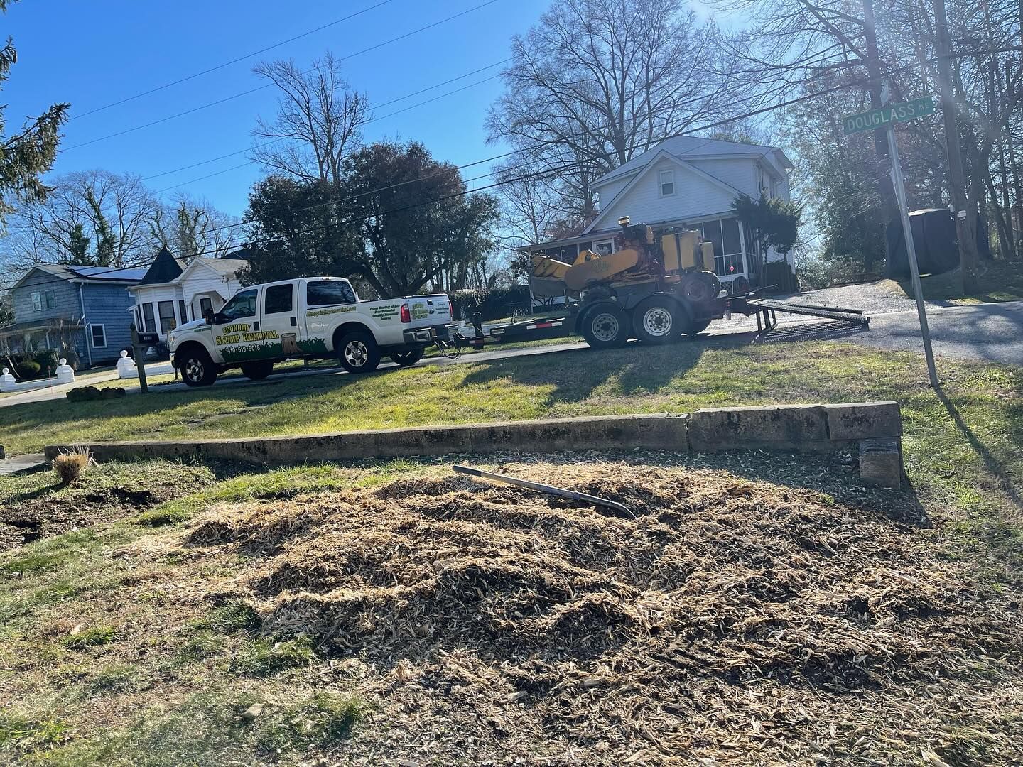 A truck and a tractor are parked in a grassy field in front of a house.