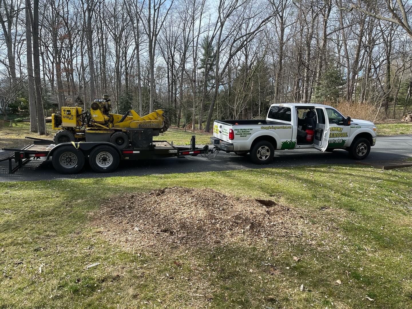 A truck is towing a stump grinder on a trailer.