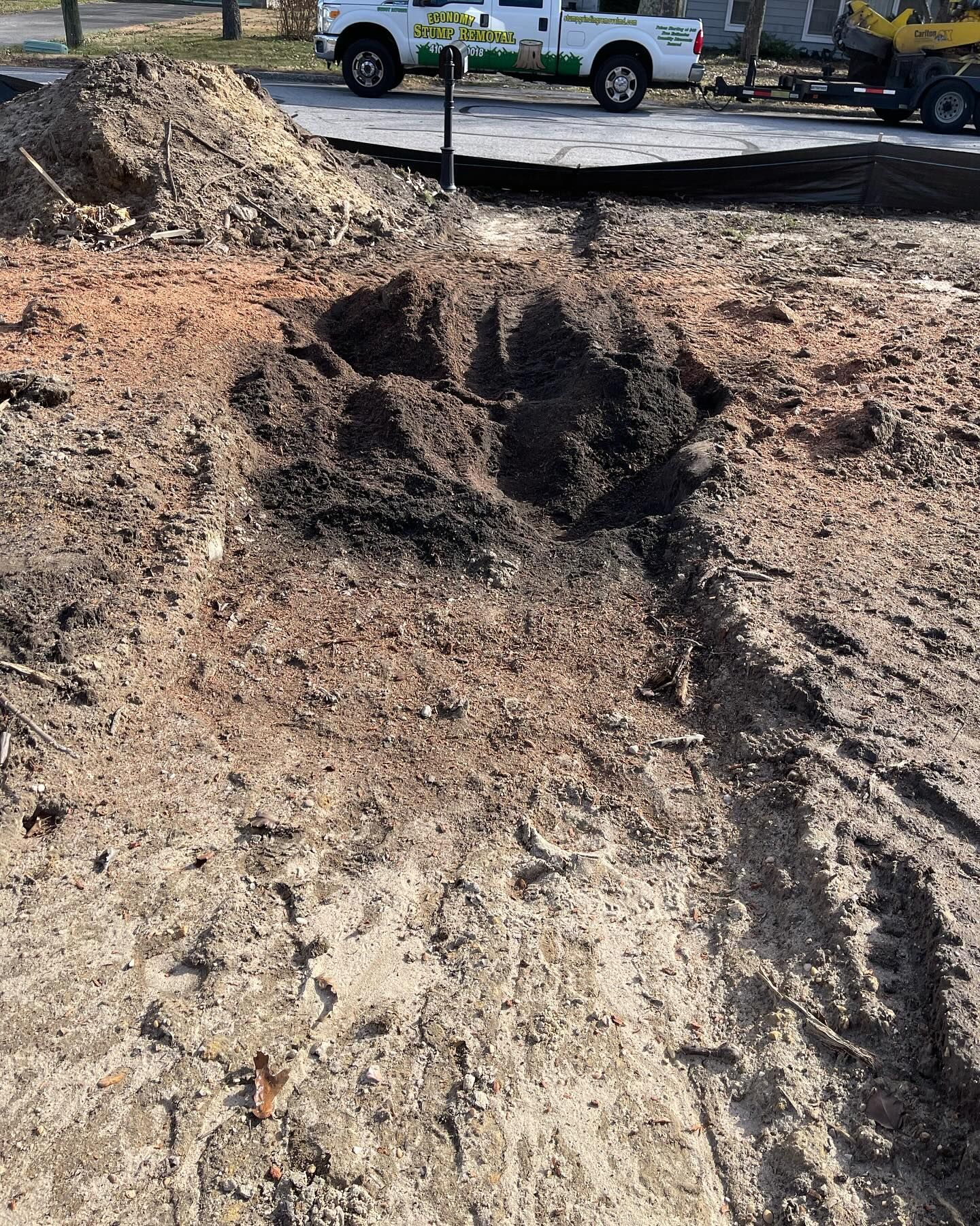 A white truck is parked next to a pile of dirt.